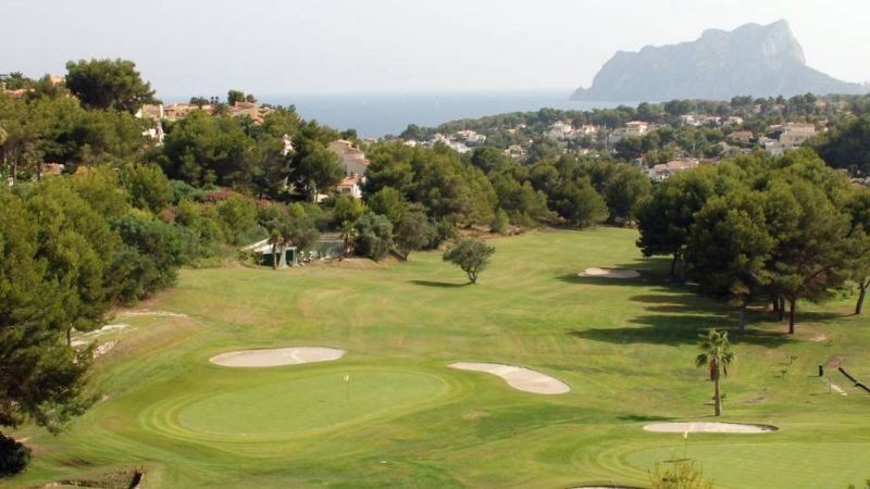 Golfbana i Alicante med gr�n fairway, bunkrar, tr�d och havsutsikt i bakgrunden.